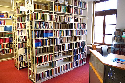Blick in einem Raum mit bis zur Decke reichenden voll bestückten Bücherregalen