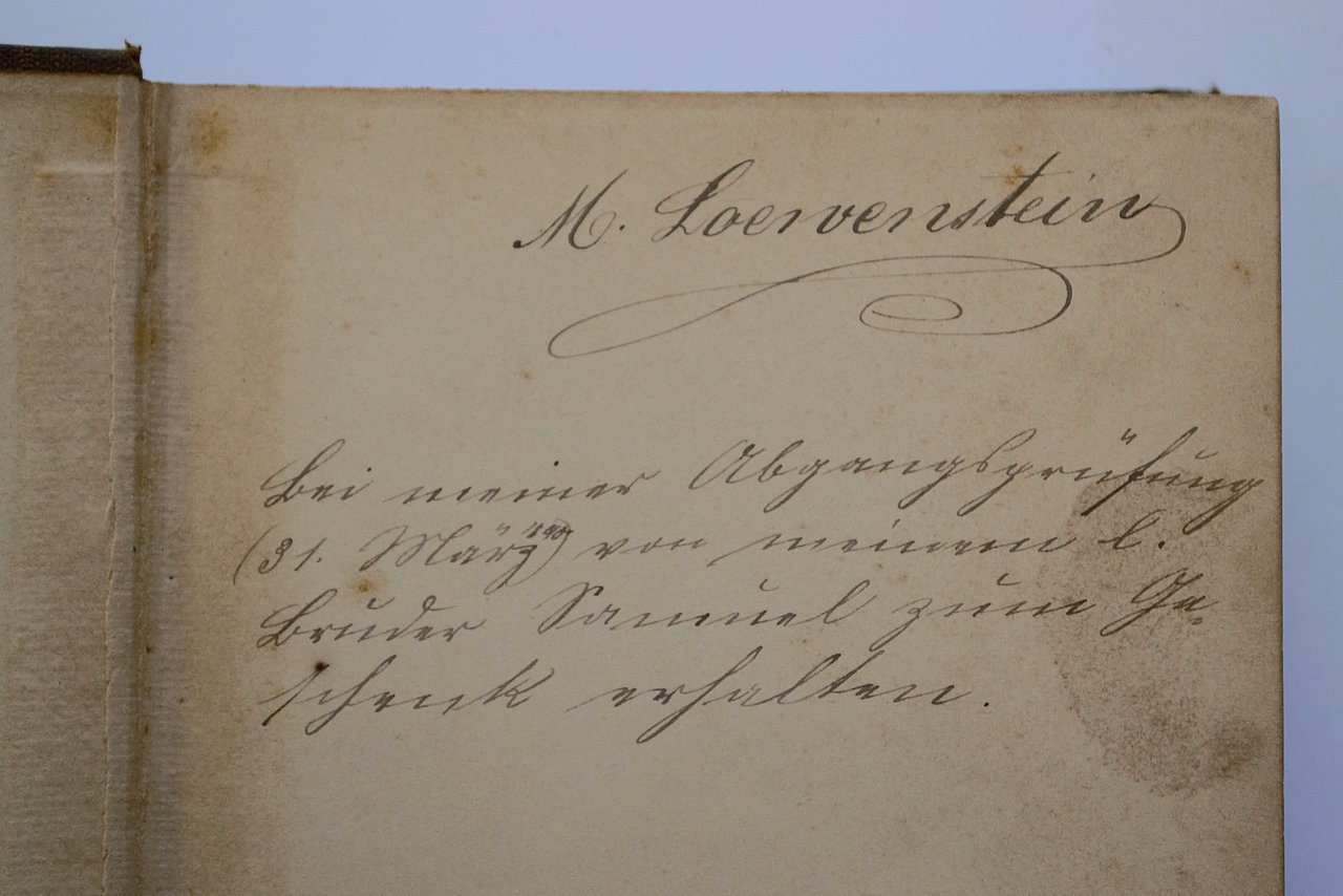 [Translate to English:] Widmung im Buch in Sütterlin. Hier steht: "M. Loewenstein // Bei meiner Abgangsprüfung (dreißigster März achtzehnhundertneunzig) von meinem ersten Bruder Samuel zum Geschenk erhalten. 