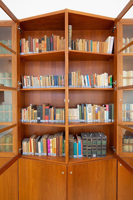 Bücherschrank, mit weitgeöffneten Türen, im Schrank: sehr viele unterschiedliche Bücher auf vier Regelebenen