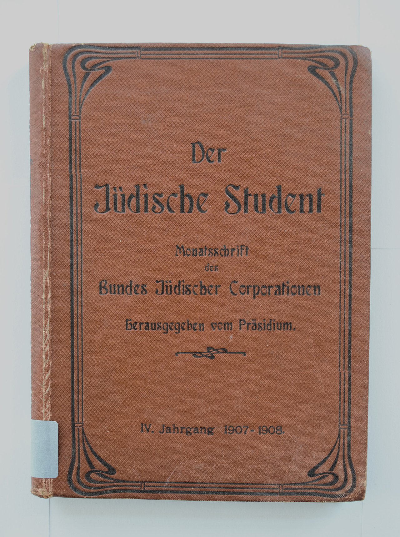 [Translate to English:] Cover des Buches "der jüdische Student" in maronenbrauner Farbe. das Cover ist künstlerisch gestaltet und eine schwarze Bordüre um Stil des Art Déco ziert den gesamten Rand.