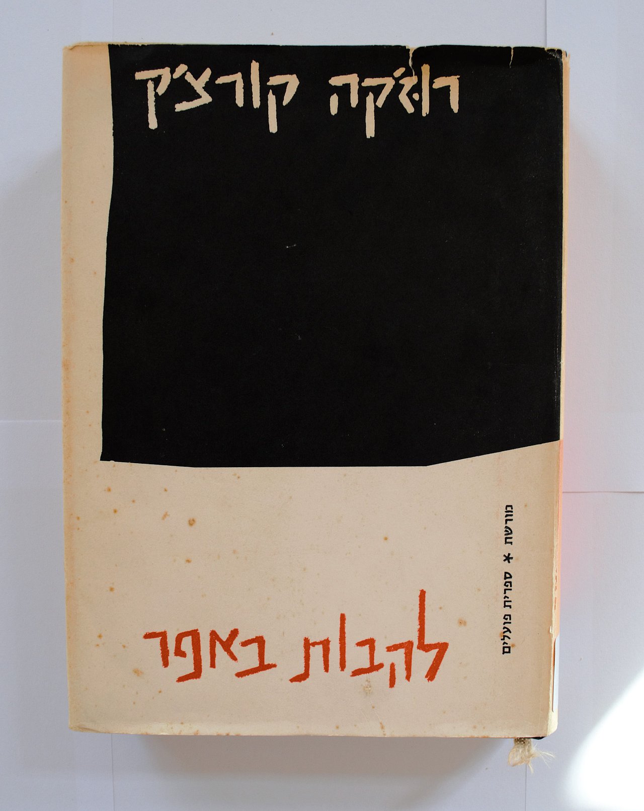 [Translate to English:] Cover des Buches mit dem hebräischen Titel: Ruz'ka Korchak: "Lehavot be'fer". Der Umschlag des Buches ist schwarz und weiß, der Name des Autors ist in weißen buchstaben vor schwarzem hintergrund geschrieben, der Titel des Buches steht unten am Seitenrand und ist in roten Buchstaben geschrieben. 