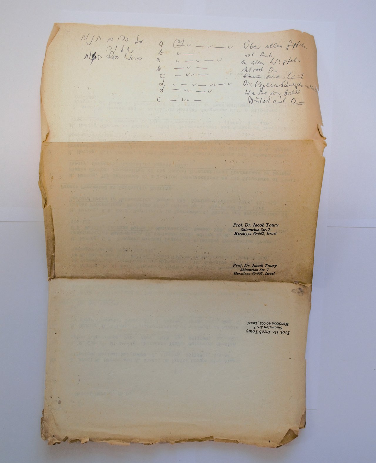 [Translate to English:] Handgeschriebener Text in hebräischer Sprache auf der Rückseite von einem Brief. Es ist ein text mit Reimschema, er wurde mehrmals überarbeitet. Vermutlich ist er mit Bleistift und Kugelschreiber geschrieben. Der Text bedeutet übersetzt:"Über allen Gipfeln / ist Ruh / In allen Wipfeln / hörest du / Kaum einen Laut / Die Vöglein schweigen im Walde / Warte nur, balde / Ruhest auch du". 